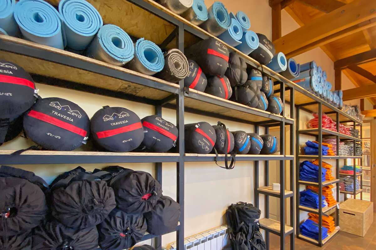 Estanterías con bolsas de dormir y aislantes enrollados para alquilar