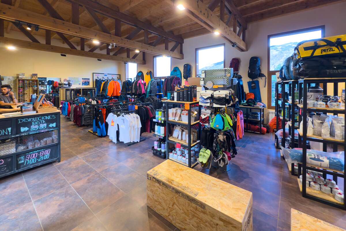 Salón de ventas con ropa, mochilas, estanterías de equipo y el mostrador de devoluciones