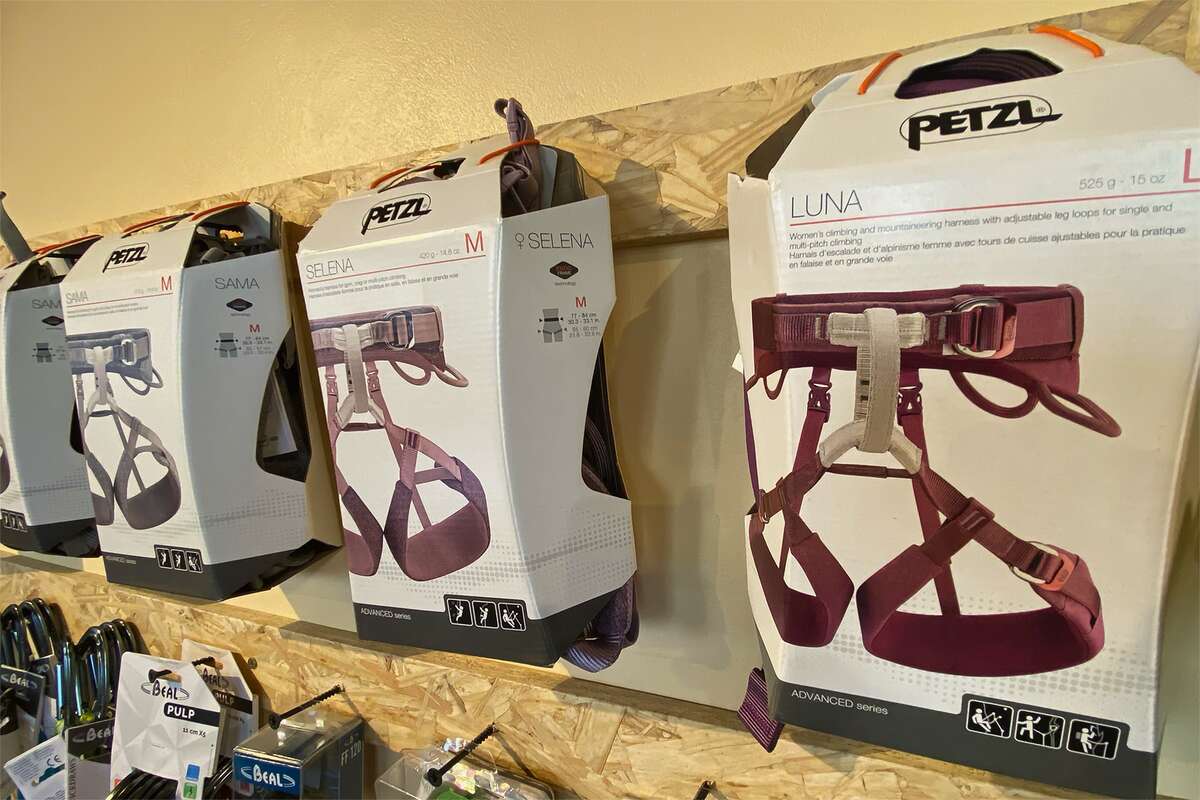 Arneses de escalada Petzl exhibidos en sus cajas sobre una pared