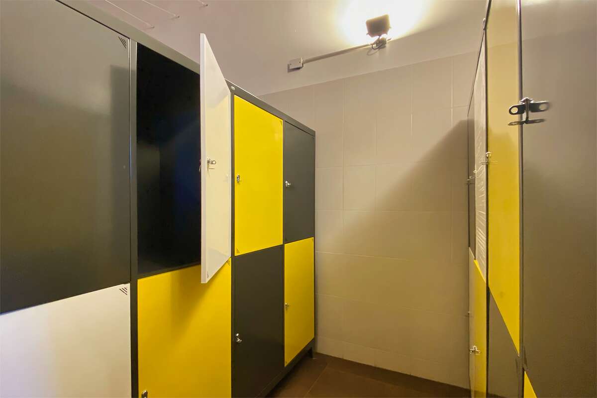 Pasillo de lockers amarillos, grises y blancos, uno con la puerta abierta