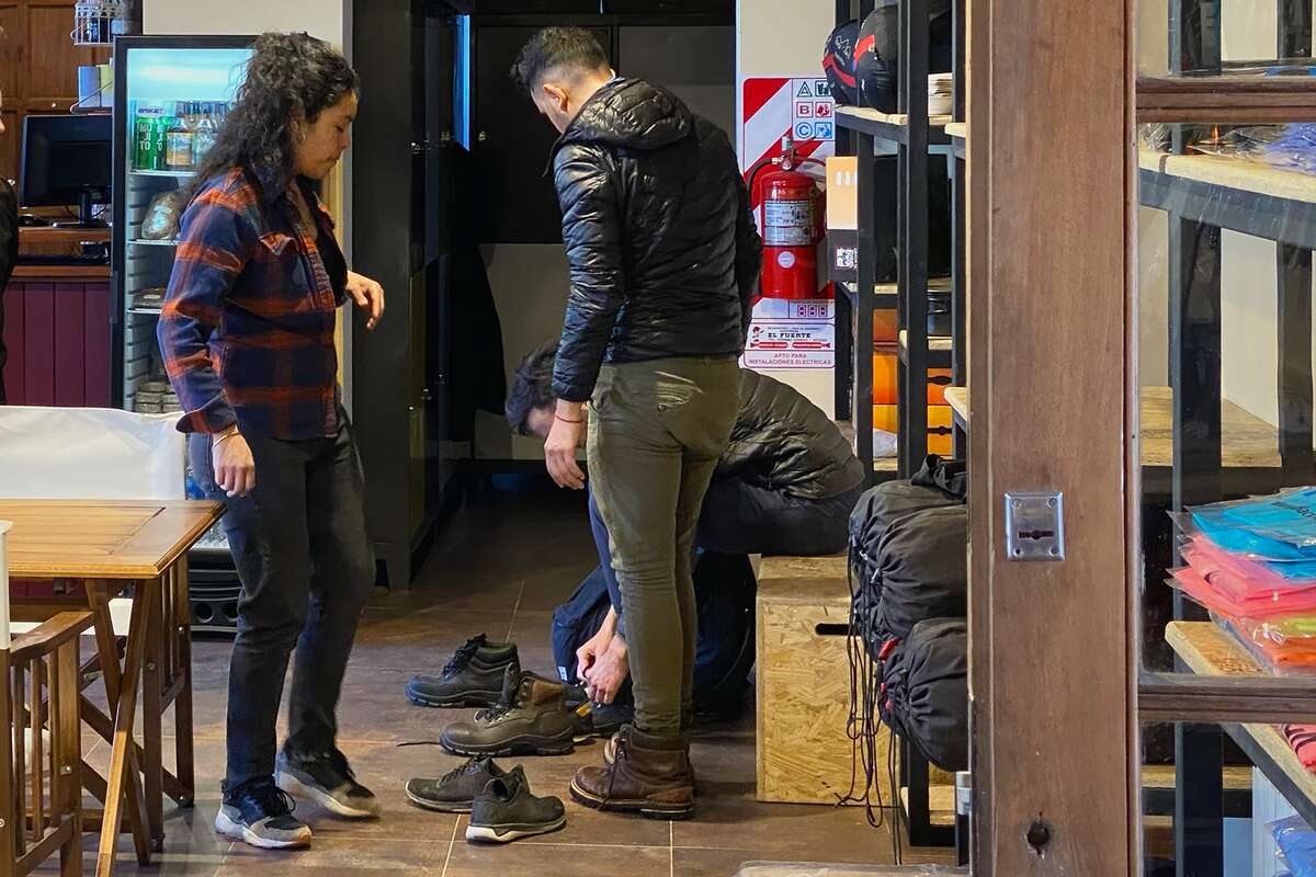 Clientes probándose botas de trekking de alquiler en el local