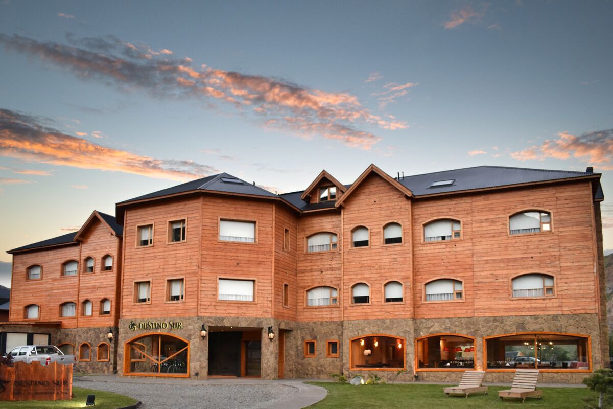 Three-story wood and stone hotel façade at sunset under pink clouds