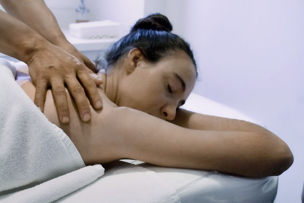 Woman lying on a massage table receiving a shoulder massage