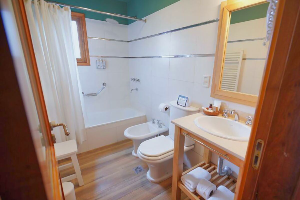Bathroom with a bathtub, toilet, bidet and a sink with a wood-framed mirror
