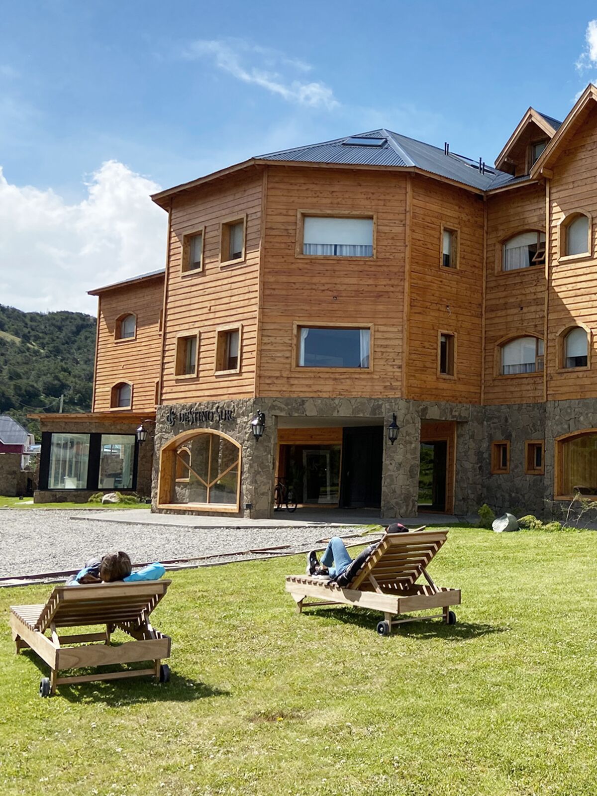 Guests on wooden loungers on the garden lawn, in front of the hotel