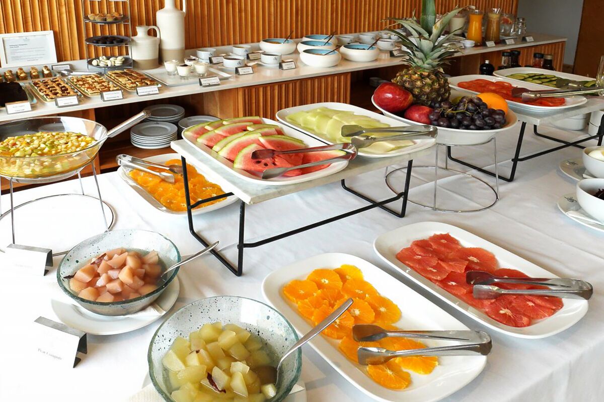 Buffet with fresh cut fruit, pineapple, cereals and dishes of fruit in syrup