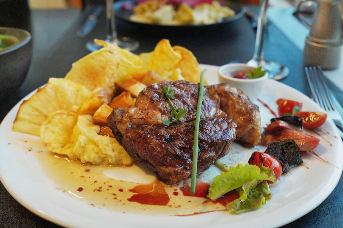 Plate of meat with homemade chips, mashed potatoes and roasted tomatoes