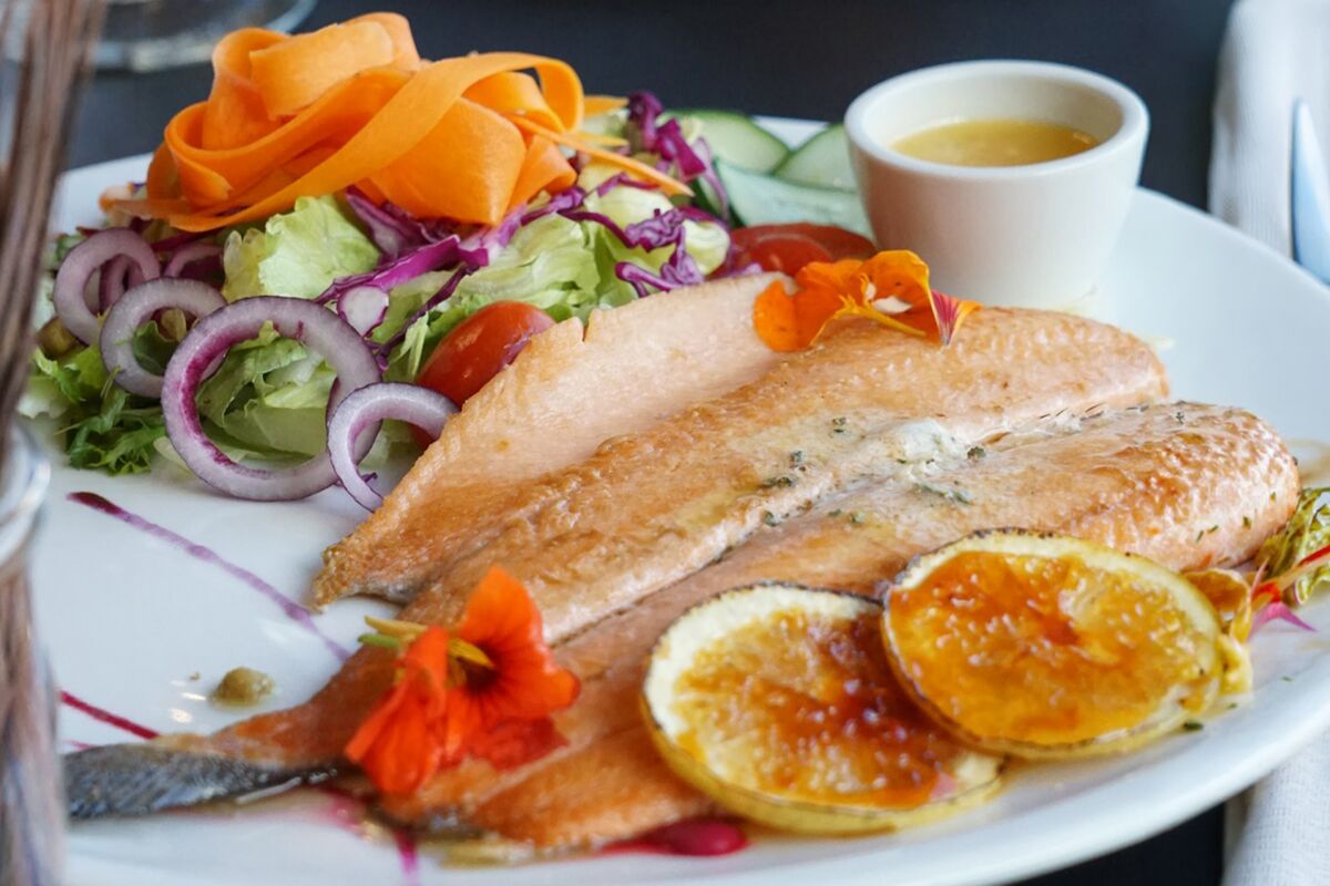 Fish fillet with grilled orange slices and a colorful salad