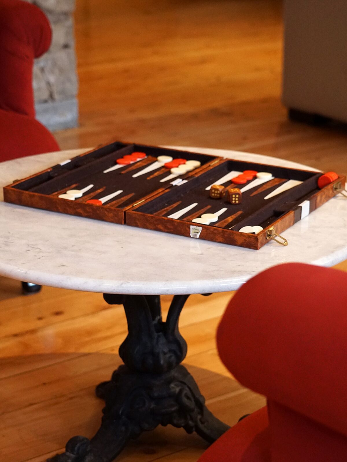 Backgammon board on a marble table between red armchairs