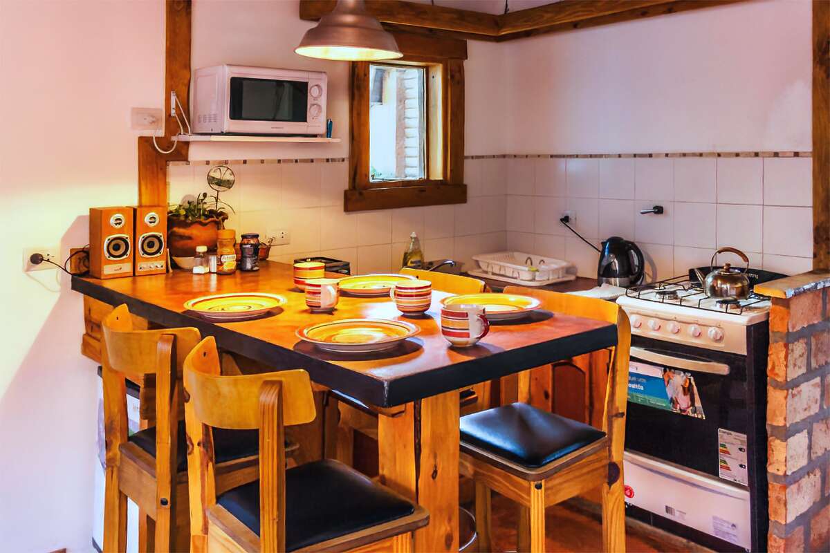 Kitchen-dining room with a wooden bar, stools, microwave and gas stove