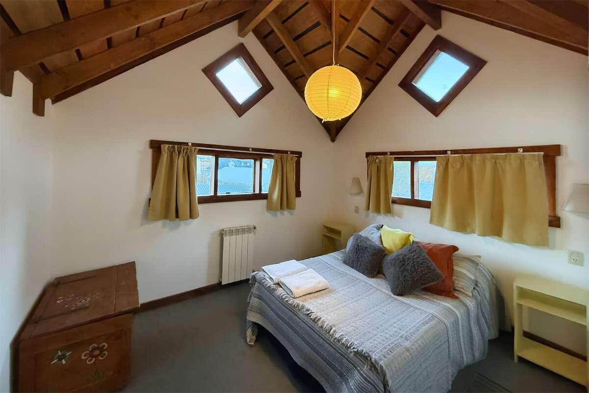 Upstairs bedroom with a double bed, windows and wooden ceiling