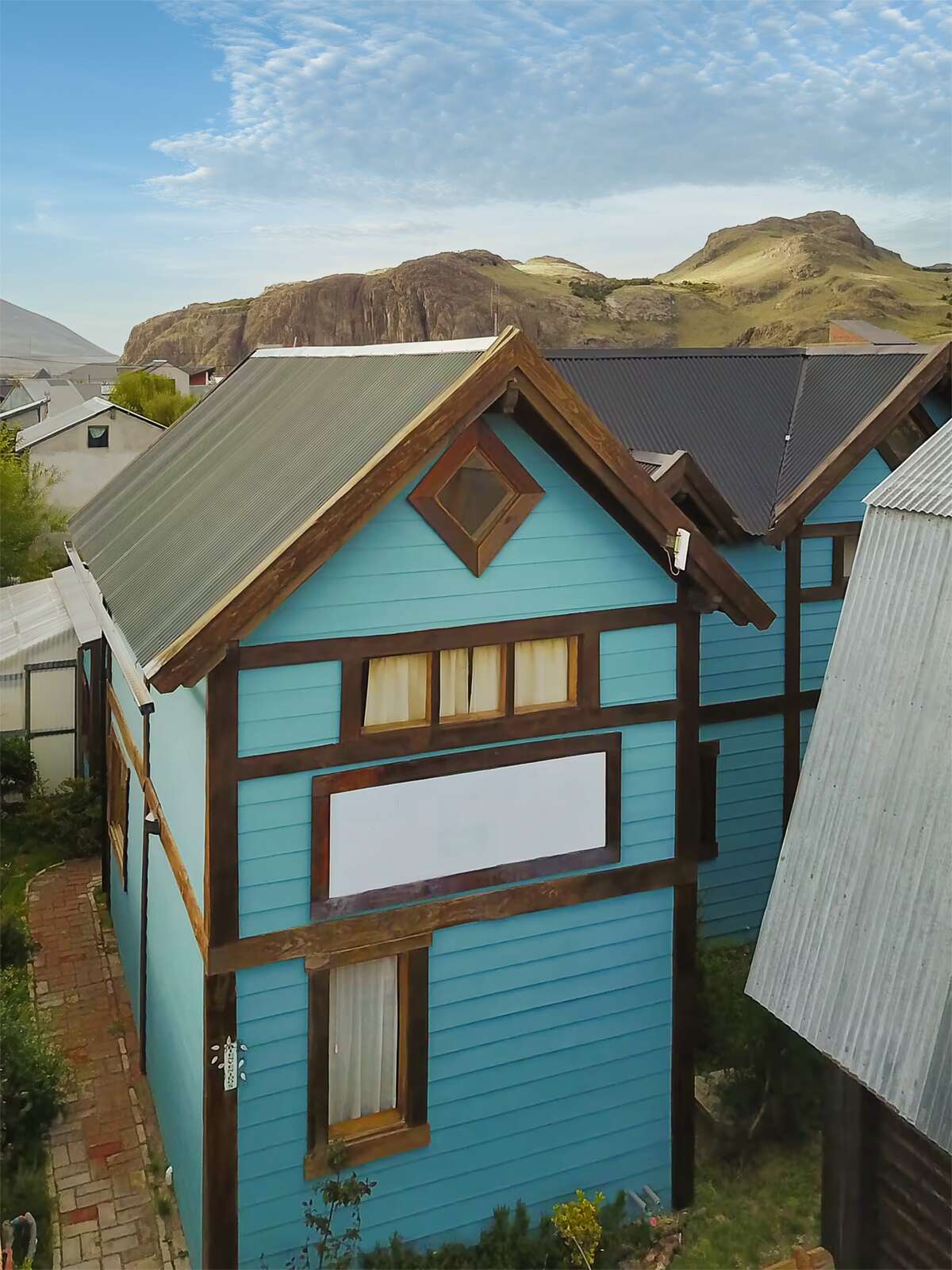 Light-blue cabin with the El Chaltén mountains behind