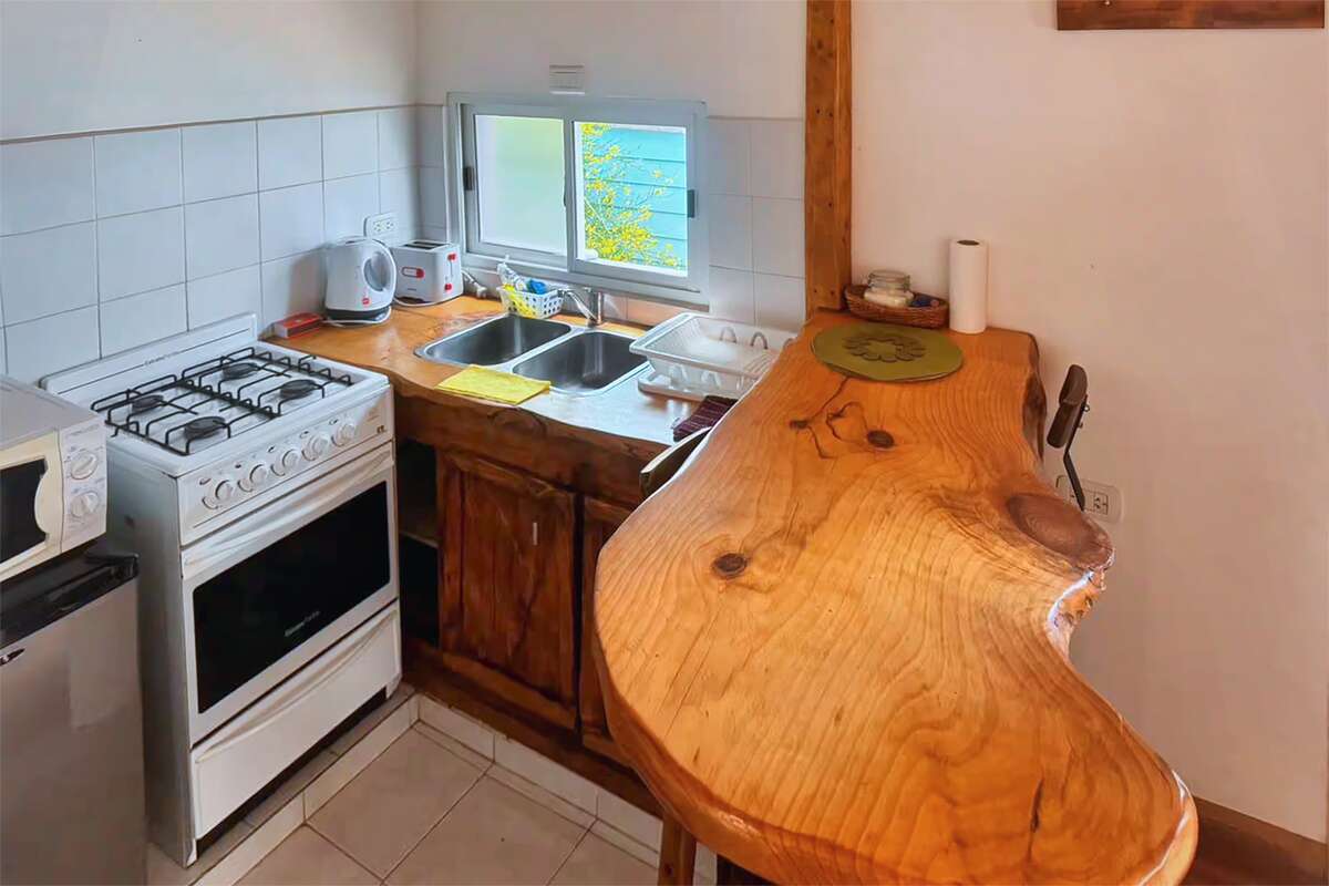 Kitchen with a four-burner gas stove, double sink and wooden bar