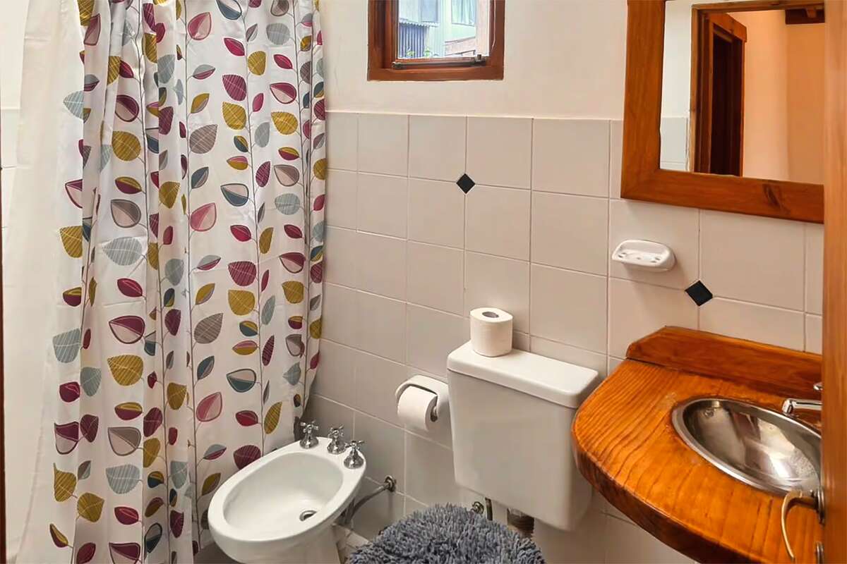 Bathroom with curtained shower, bidet, toilet and wooden sink