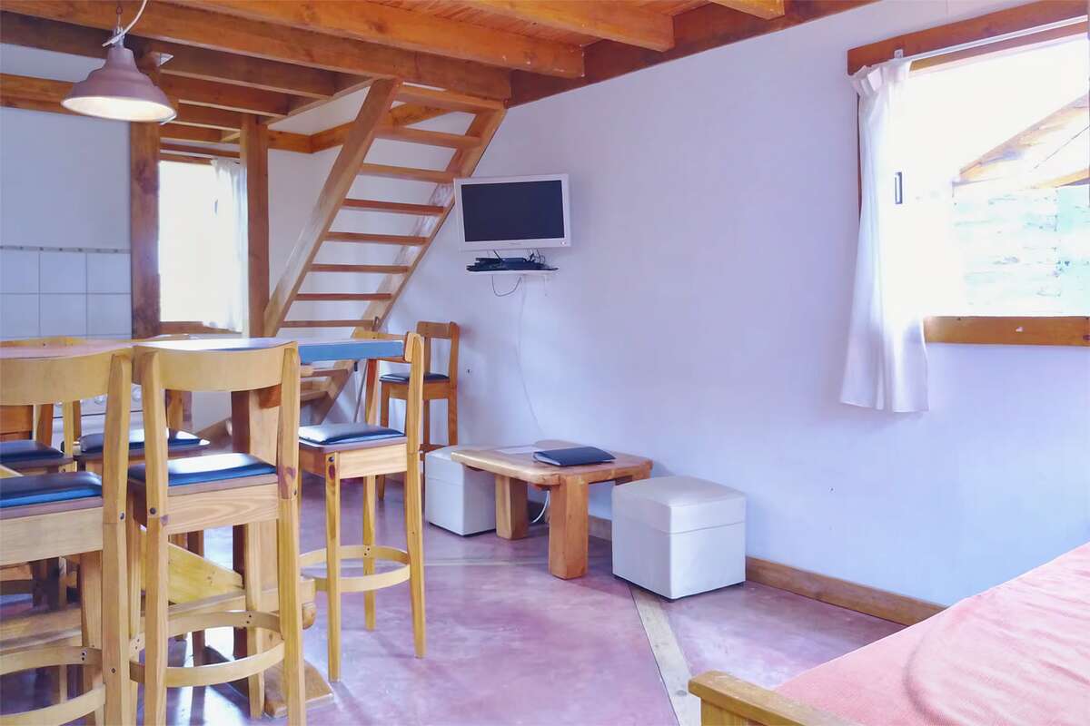 Dining area with a bar and stools, TV and stairs to the upper floor