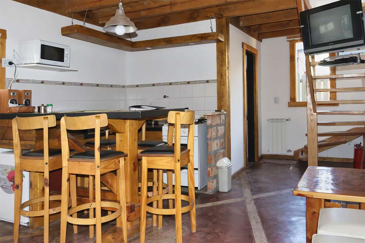 Kitchen-dining room with a bar, stools, microwave and stairs