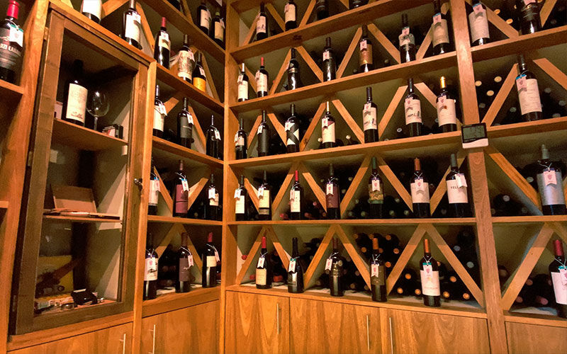 Cava de madera con estantes llenos de botellas de vino