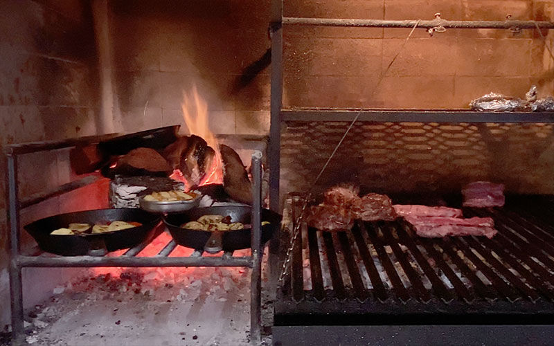 Asador con brasas y cortes de carne sobre la parrilla