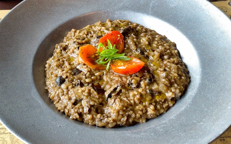 Risotto de hongos con tomates cherry y albahaca en plato hondo