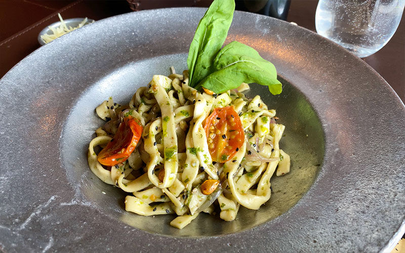 Fettuccini con pesto y tomates confitados en plato hondo