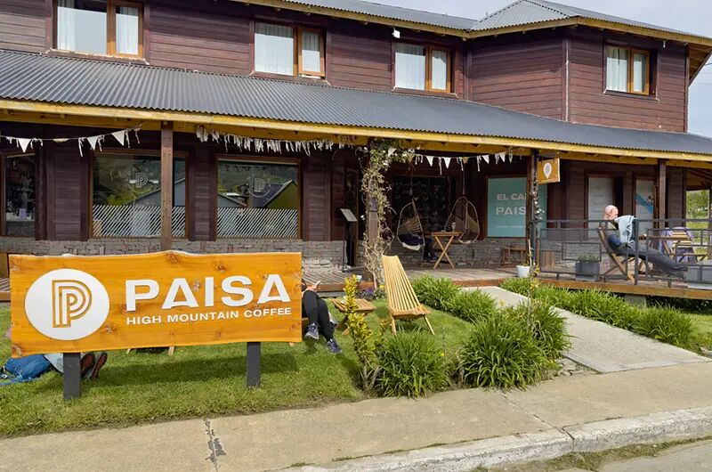 Frente del local con el cartel de Paisa sobre el césped y la galería de madera
