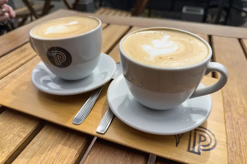 Dos cafés con latte art sobre una bandeja de madera