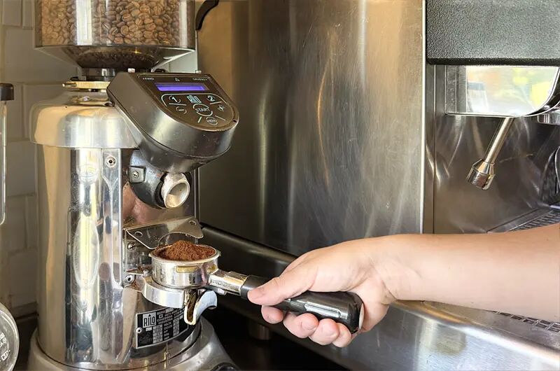 Barista moliendo café en el portafiltro