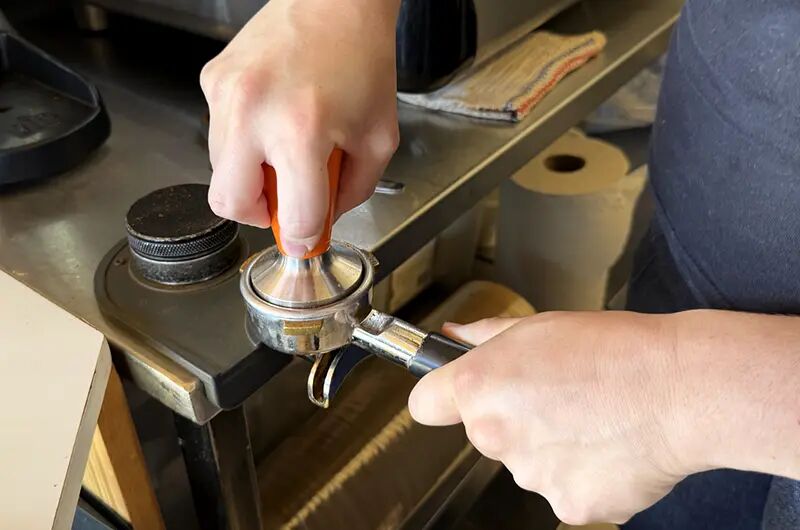 Barista compactando el café en el portafiltro