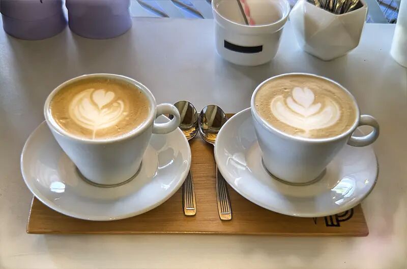 Dos cafés con corazones de latte art en una bandeja