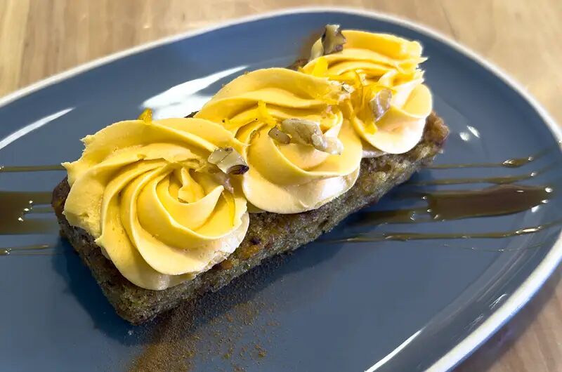 Porción de carrot cake con crema en un plato gris