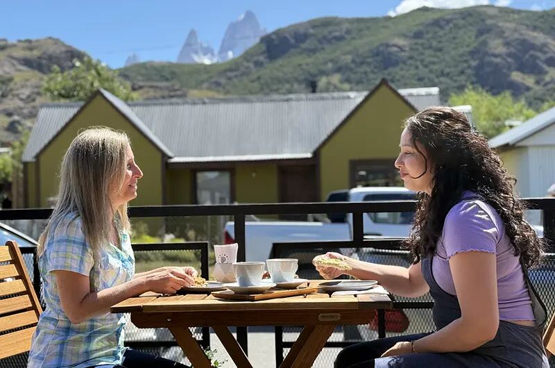 Dos amigas en una mesa de la galería, con el cerro Fitz Roy al fondo