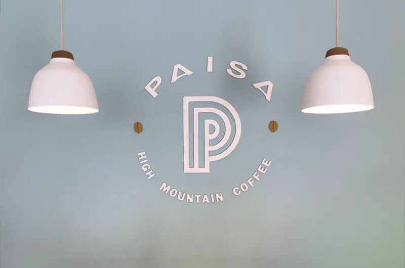 Logo de Paisa pintado en la pared entre dos lámparas