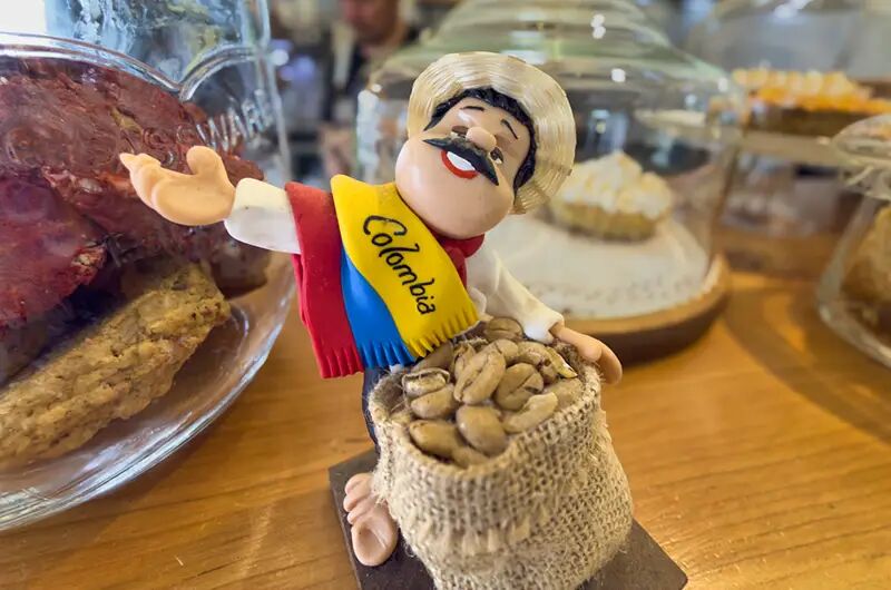 Muñeco de caficultor con una bolsa de granos y bandera de Colombia