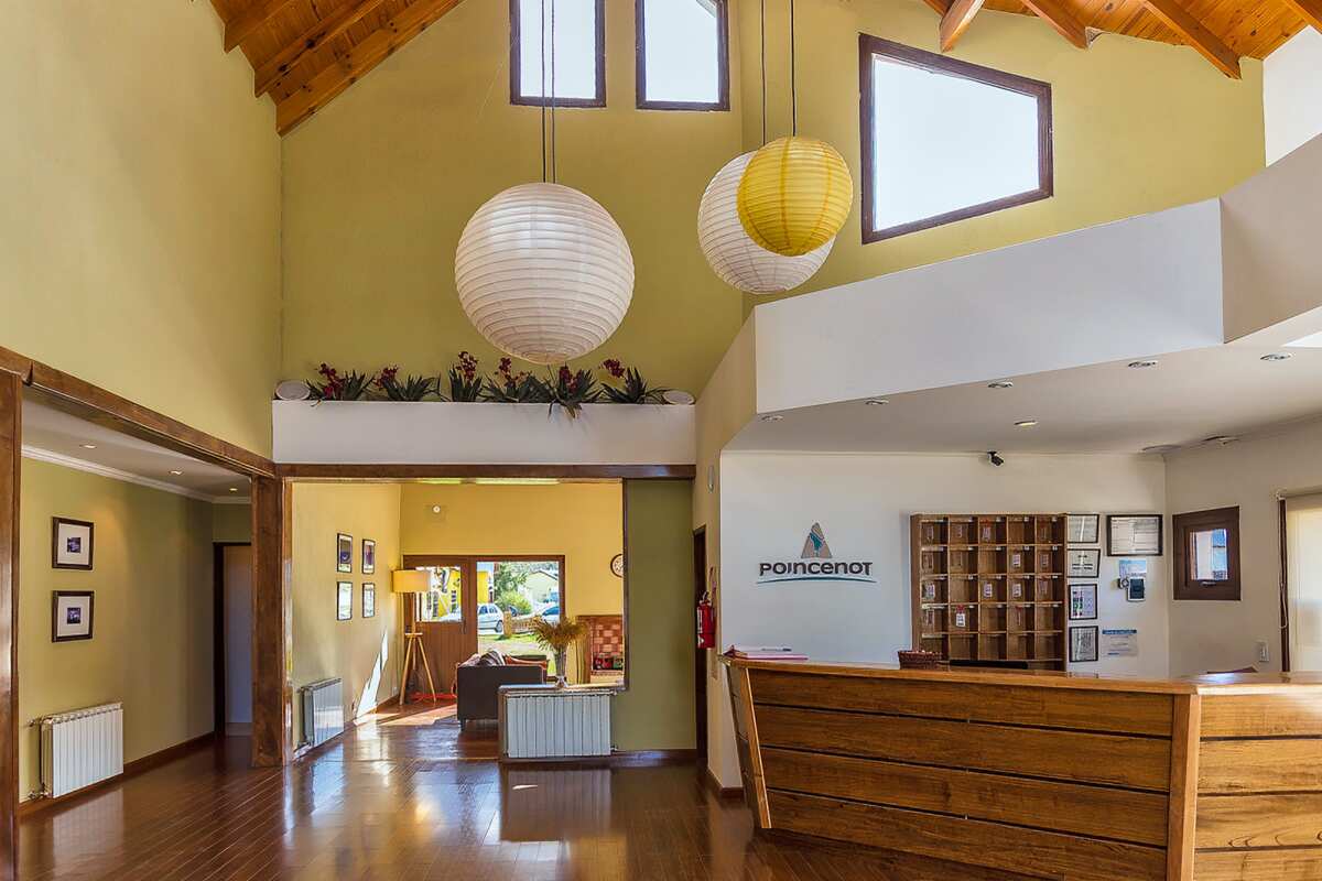 Reception with a wooden desk, key cubbies and a double-height hall with paper lanterns