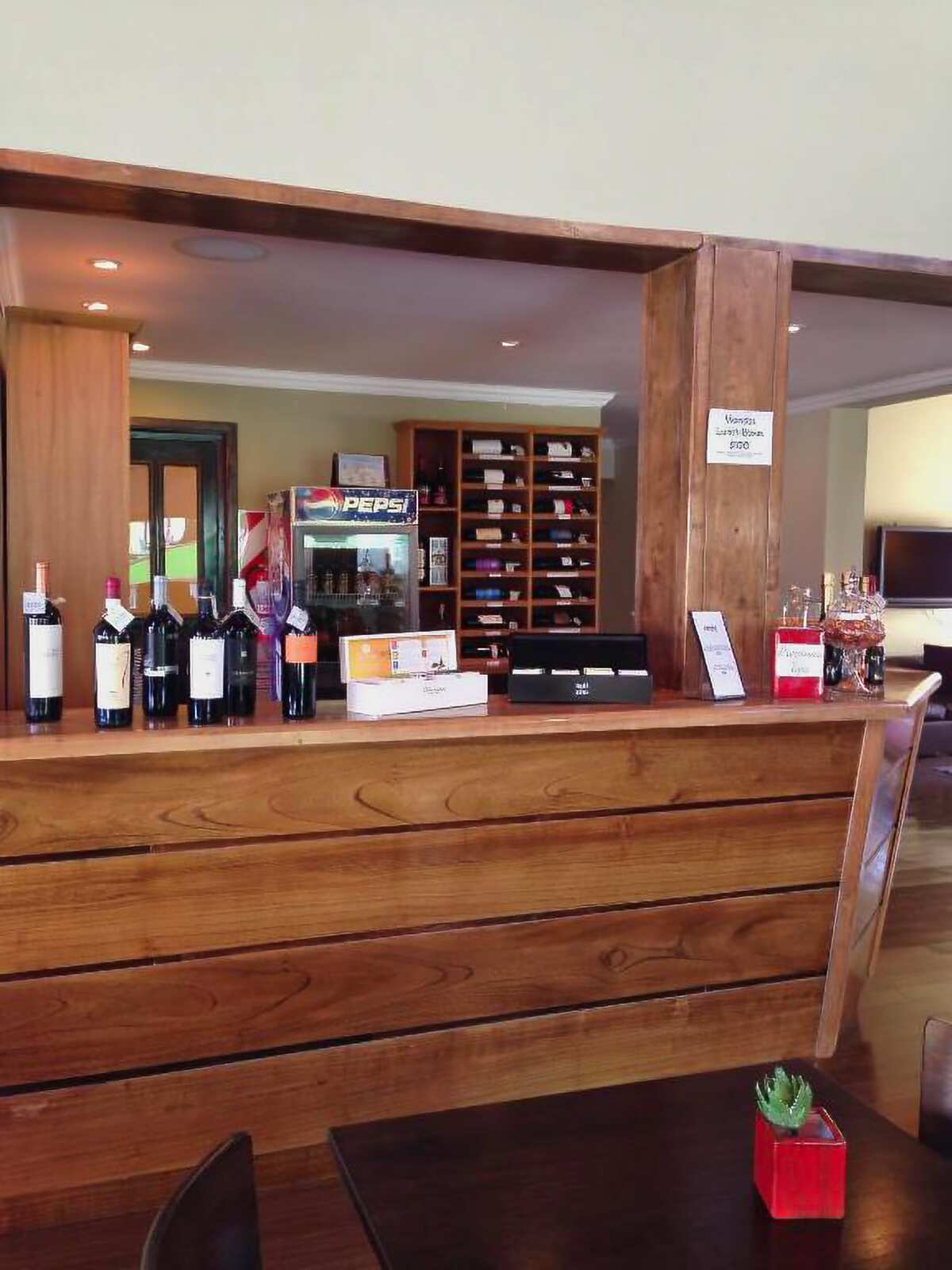 Wooden bar with wine bottles and a drinks fridge in the back