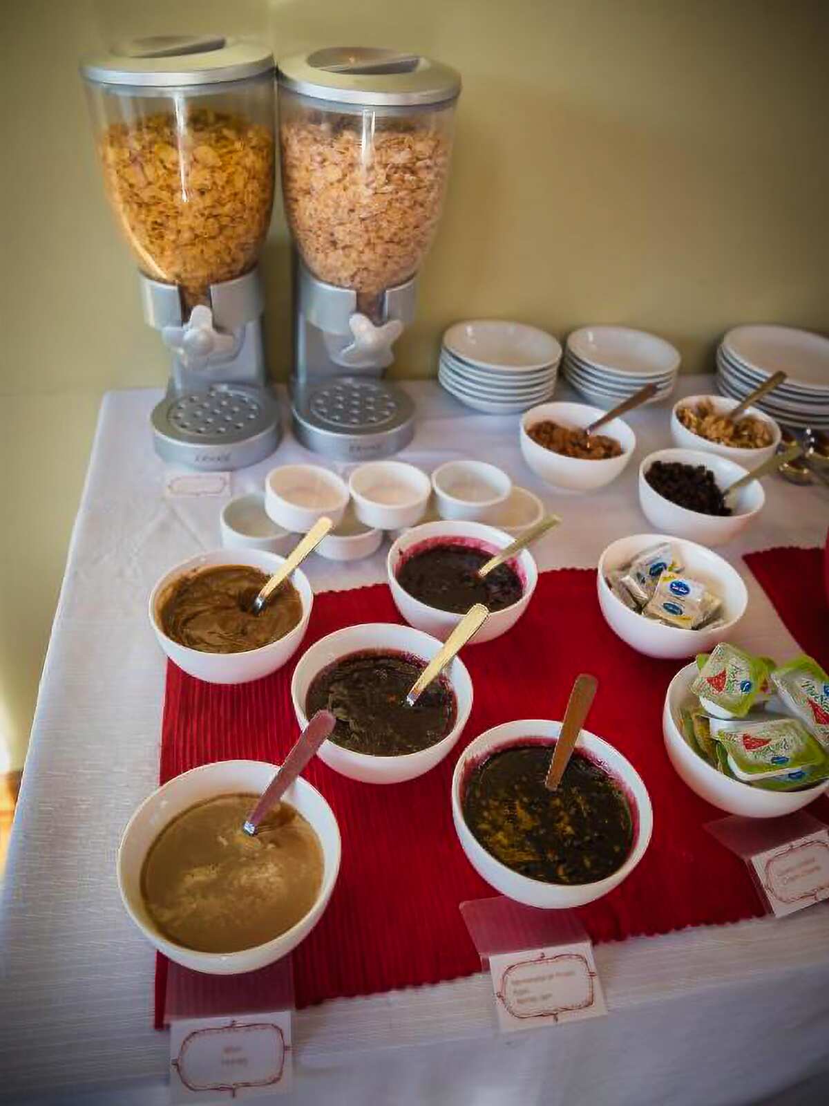 Cereal dispensers and bowls of spreads and jams on the breakfast table