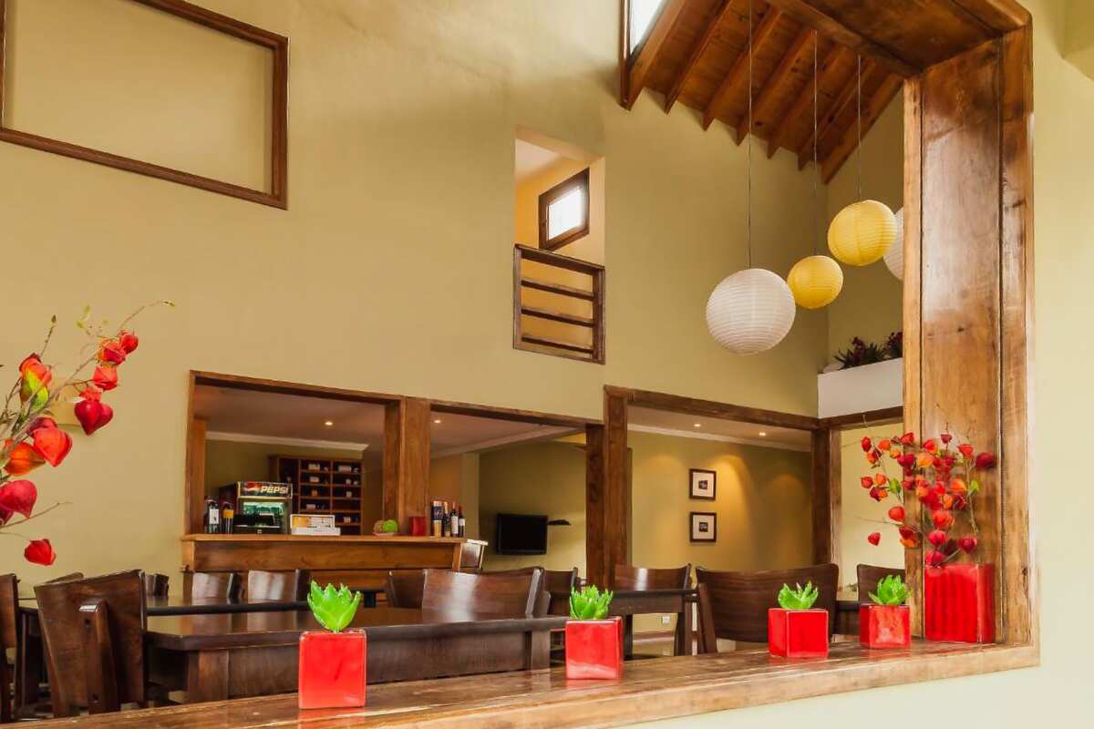 Breakfast room with wooden tables, red flowers and a bar in the back