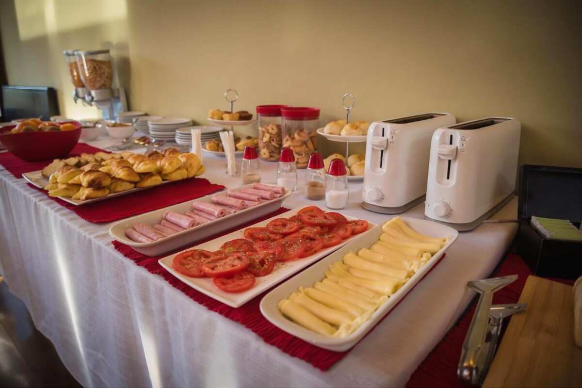 Buffet table with croissants, cold cuts, tomatoes, cheese and toasters