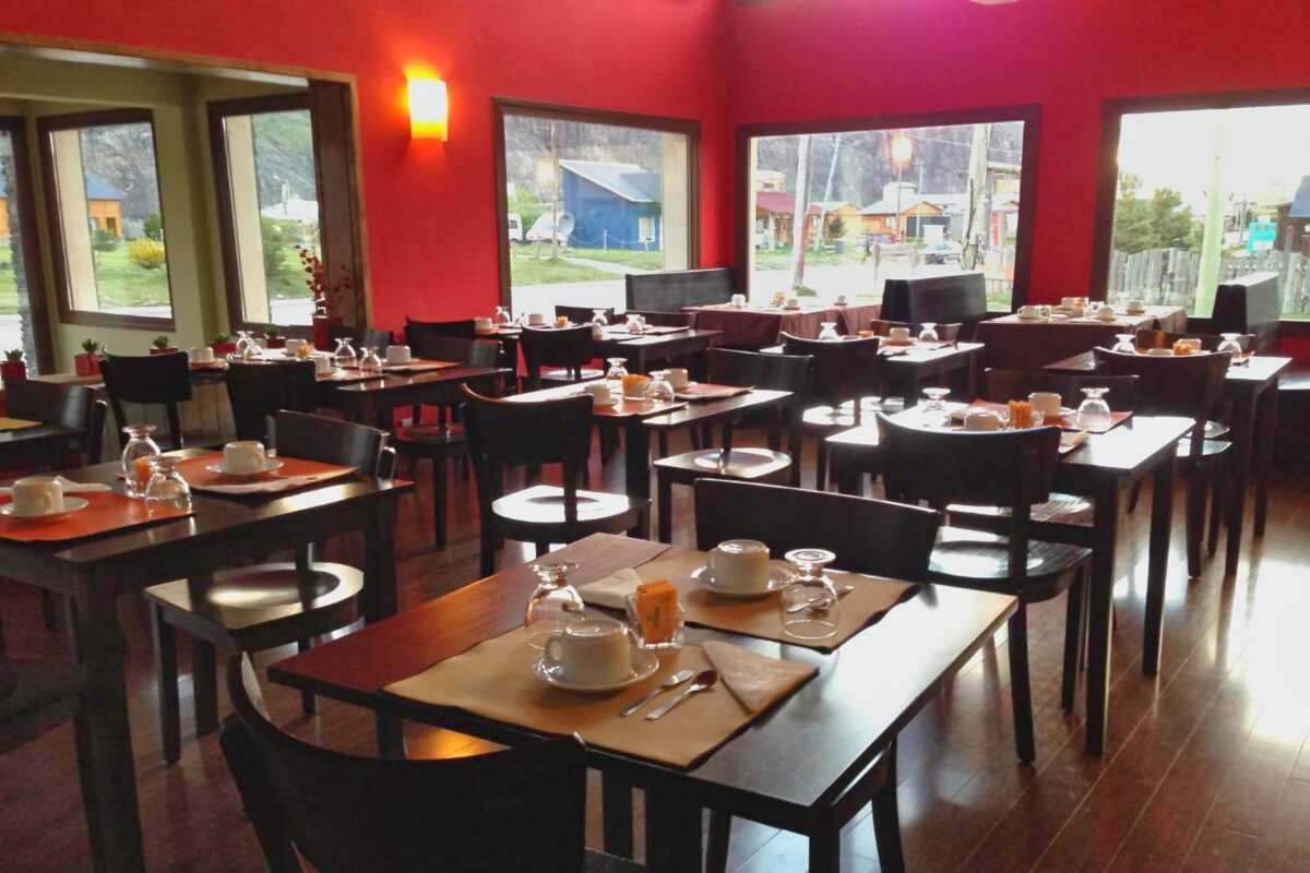 Red-walled room with set tables and large windows facing the street