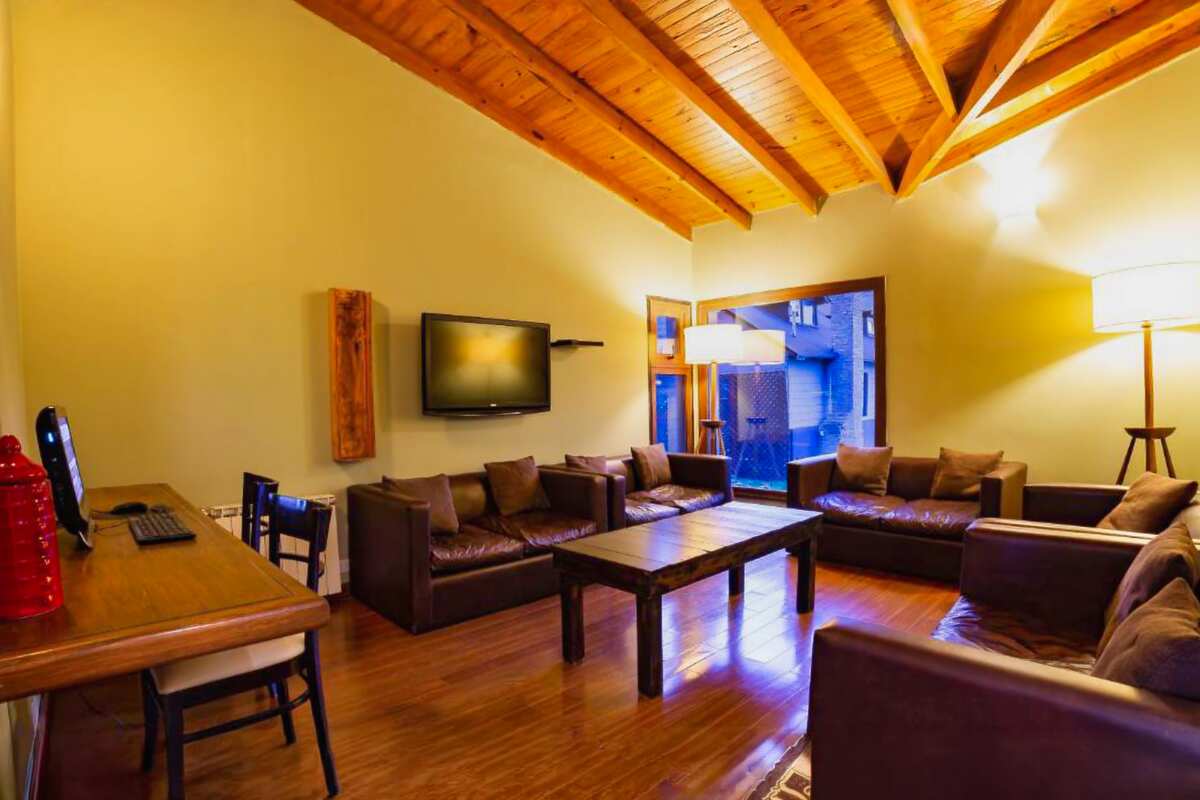 Lounge with leather sofas, TV, coffee table and a desk with a computer