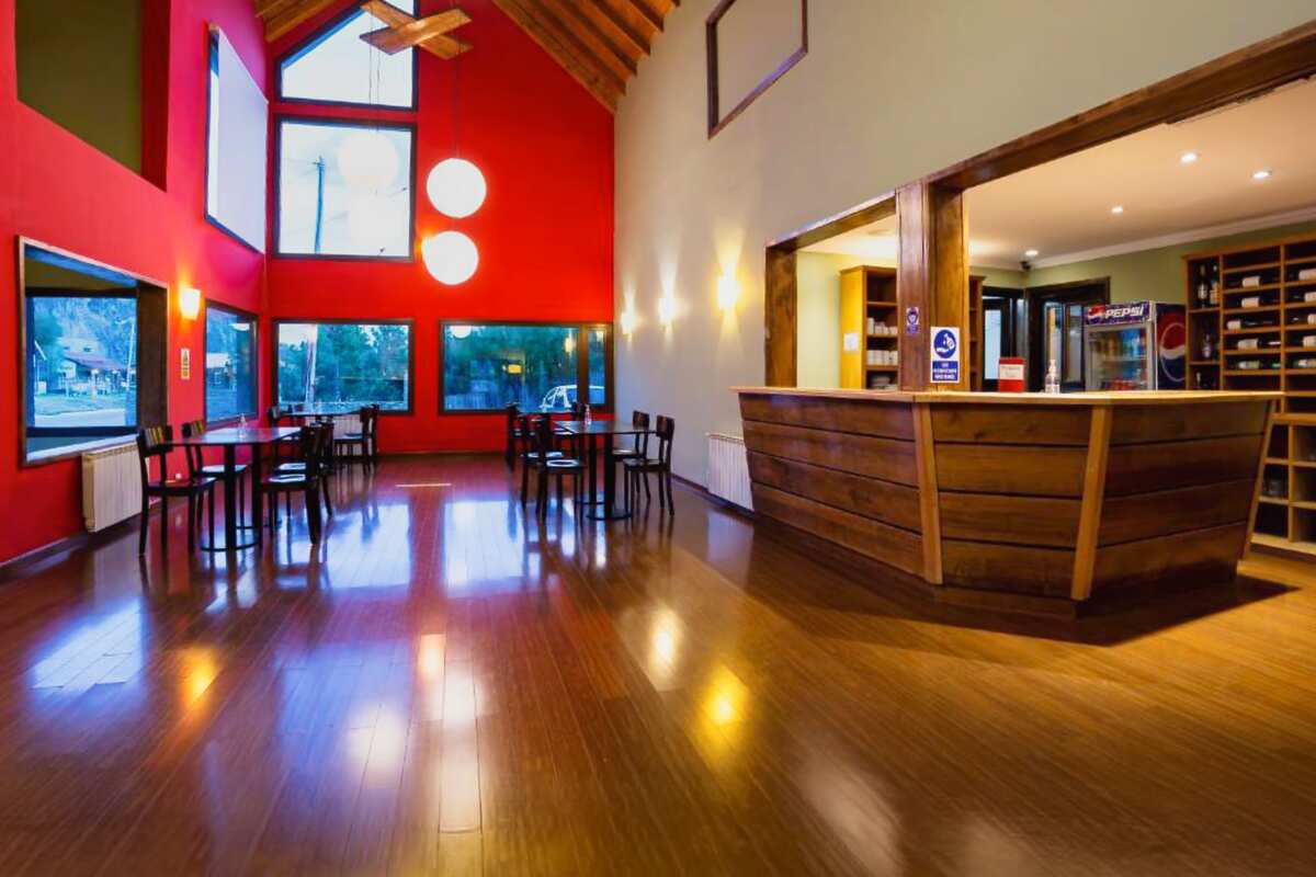 Double-height hall with red walls, tables and the wooden reception desk