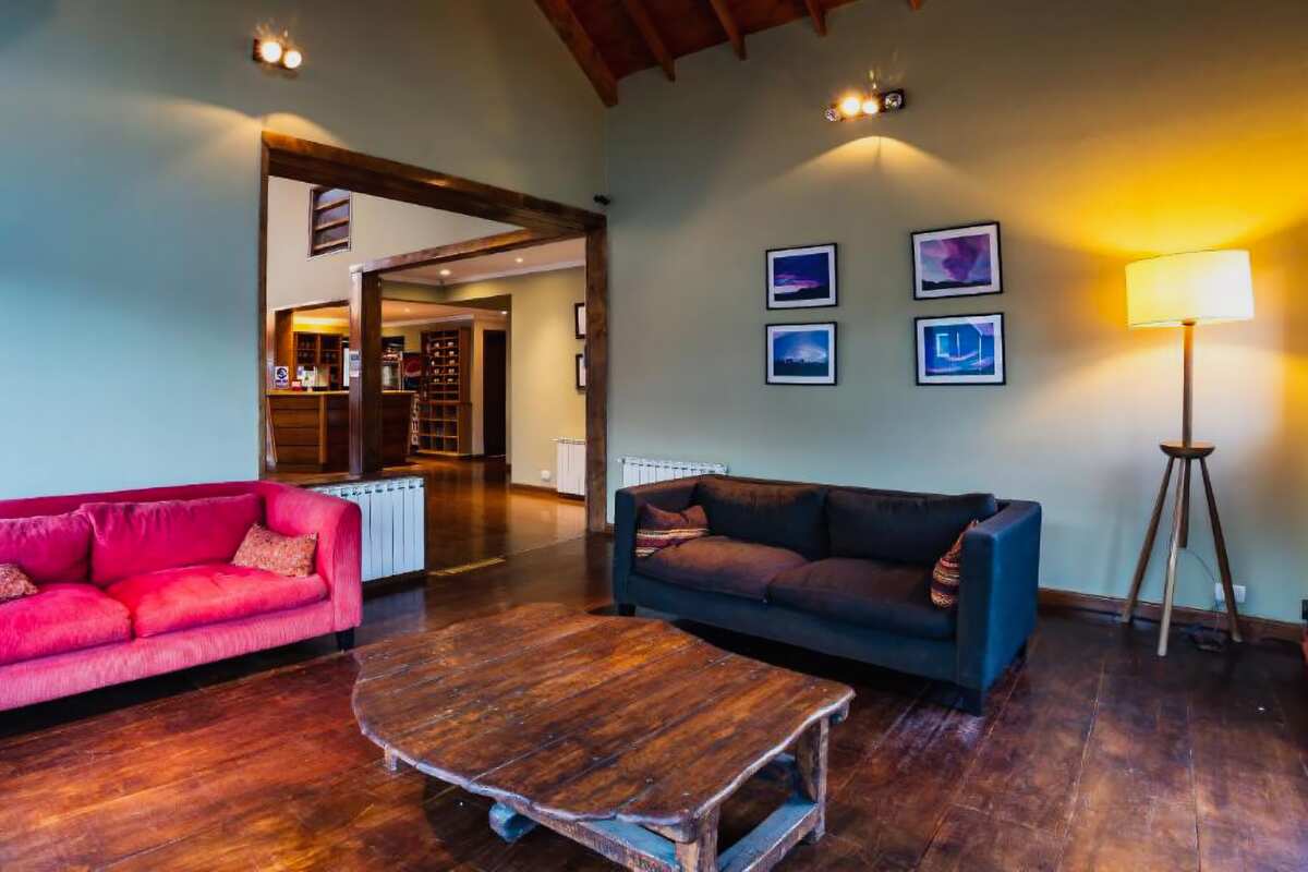 Lounge with pink and blue sofas, a rustic wooden table and framed pictures