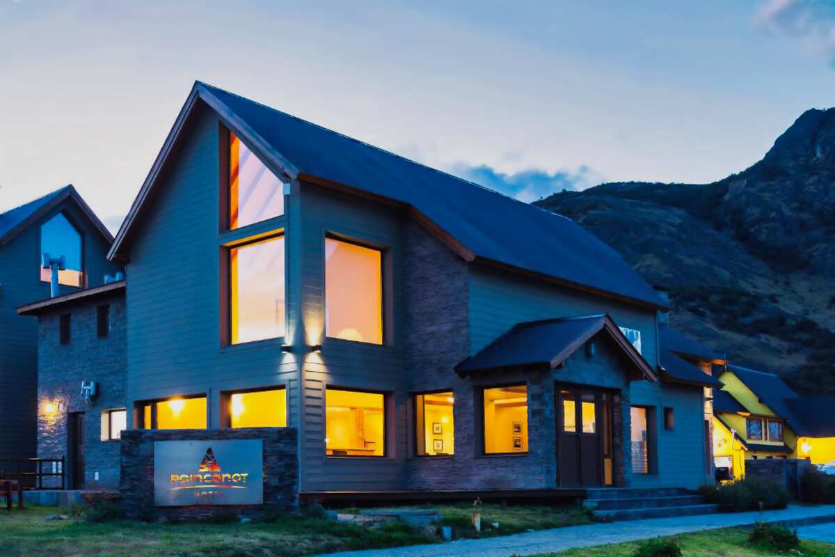 The hotel at dusk with lit windows and mountains behind