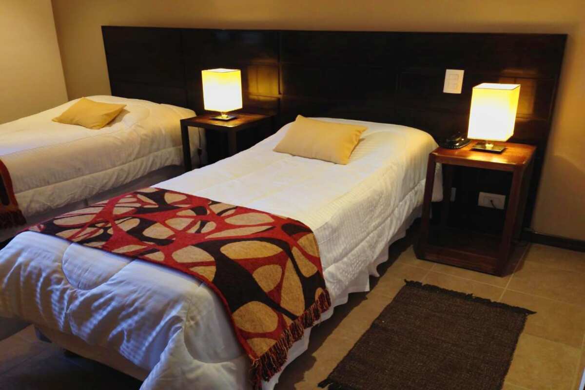 Room with two single beds, nightstands and lit lamps