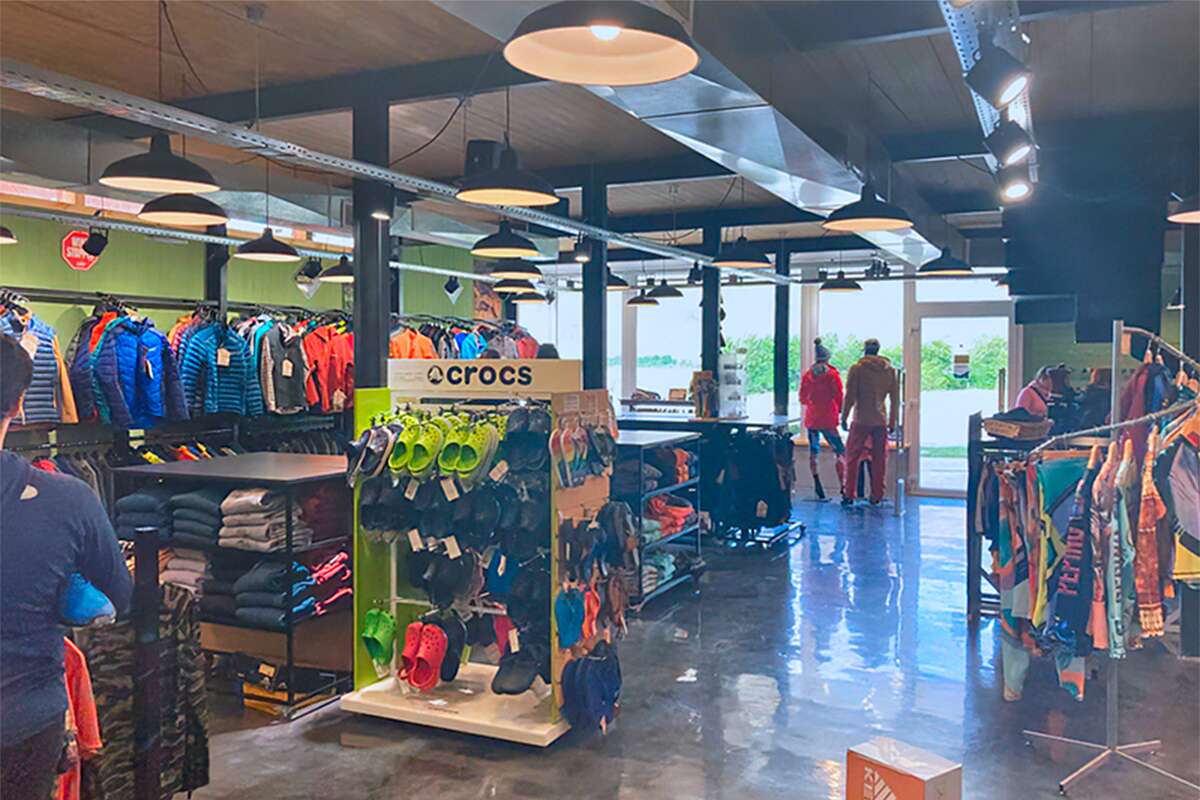 Exhibidor de calzado Crocs de colores entre percheros de ropa y ventanales