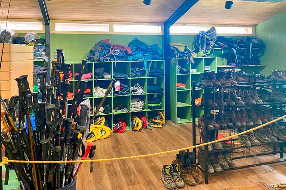 Sector de alquiler con bastones de trekking, crampones, botas y mochilas en estantes