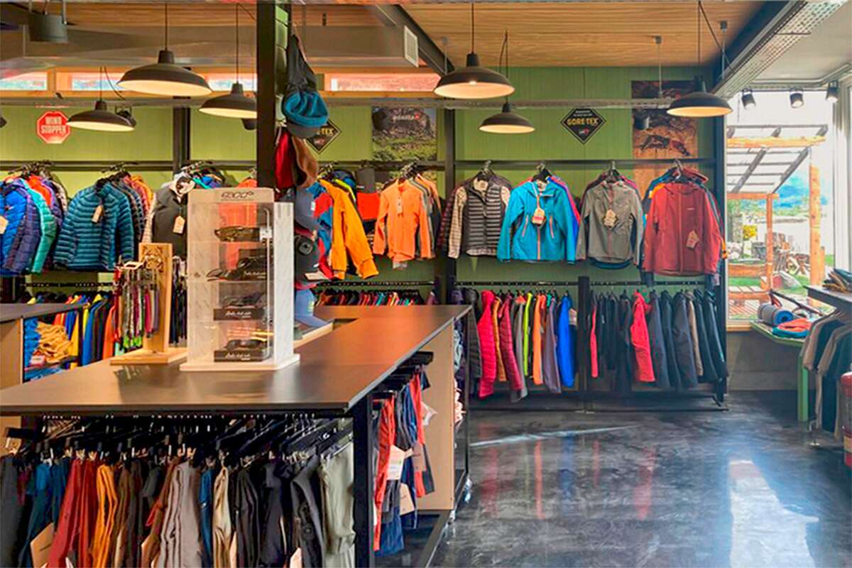 Pared de camperas impermeables de colores con carteles de Gore-Tex y Windstopper, y exhibidor de anteojos